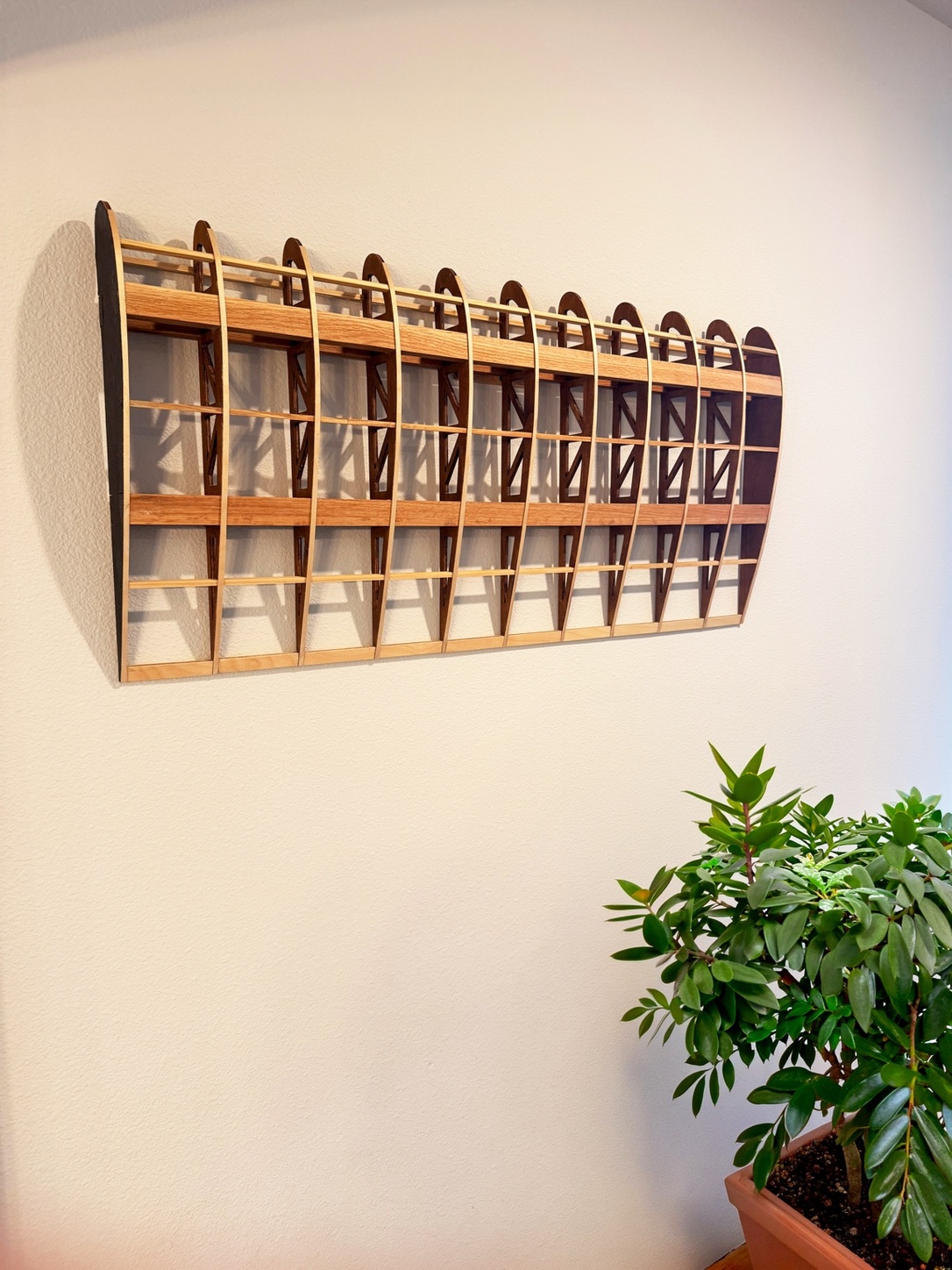Flightline Furniture Elevator
                  wing rib wall art — left profile mounted on wall — red oak — potted plant in background —
                  Corvallis Oregon